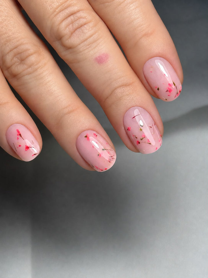 unghie ricostruite ricoperte con gel colorato rosa pastello con fiori veri